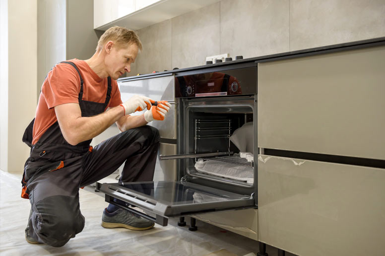 How Much Does Appliance Repair Cost: man fixing oven