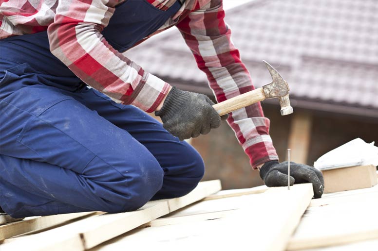 How To Get Your Roofing License: Roofer Hammering Nails Into Roof