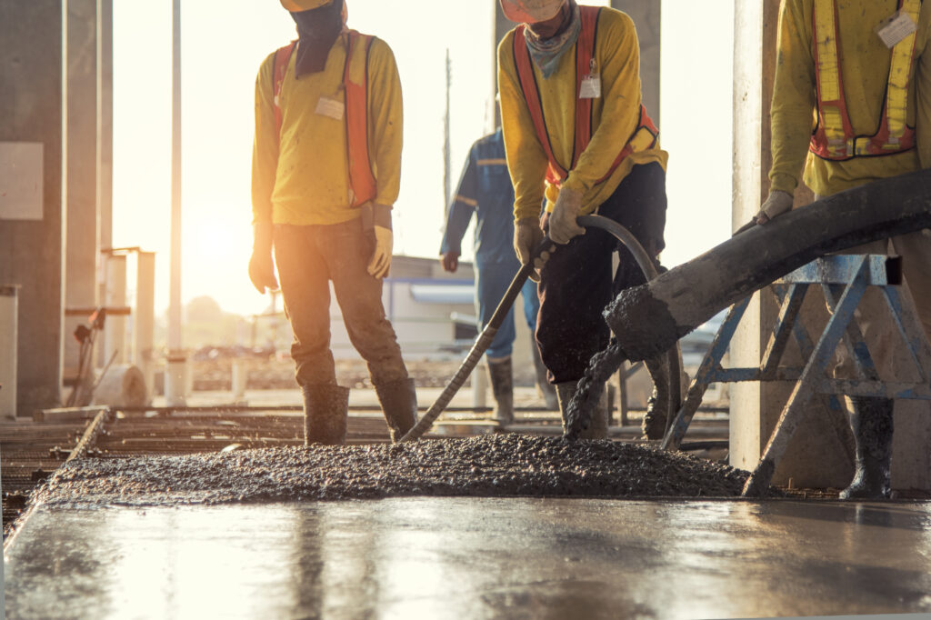 4 construction workers pouring concrete in the sunset.