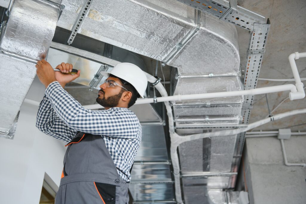HVAC technician inspecting ductwork on a ceiling