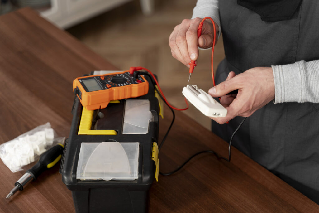Close-up of electrician testing voltage with a digital multimeter next to a toolbox.