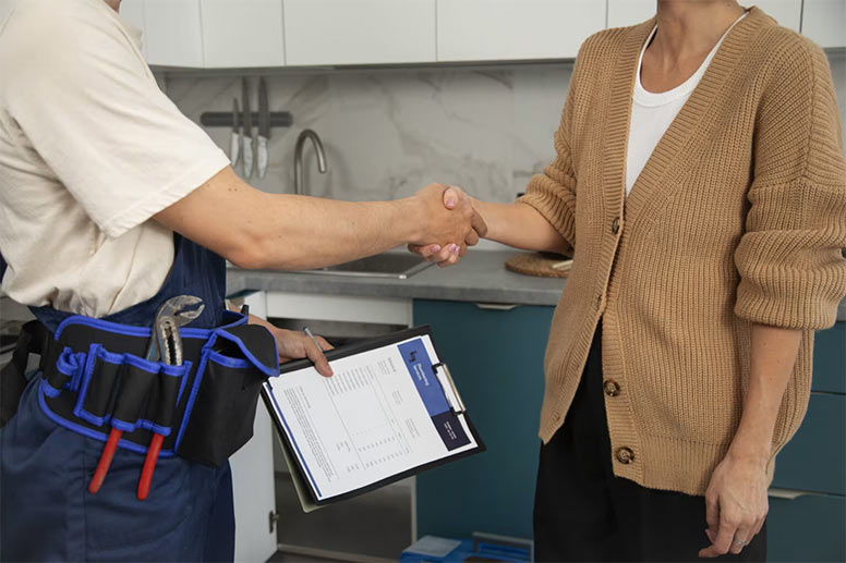 Roofer shaking hands with a homeowner while holding a clipboard with service paperwork.
