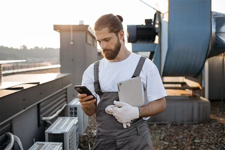 HVAC technician using a digital smart phone to review schematics in front of a HVAC unit.