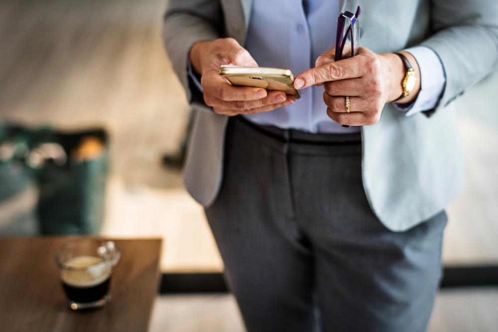 Professional checking business updates on phone in a coffee shop.