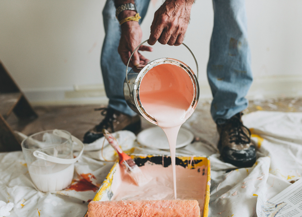 Painting contractor pouring pink paint into recipient.