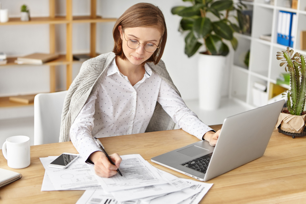 Small business owner calculating retained earnings with laptop and financial documents