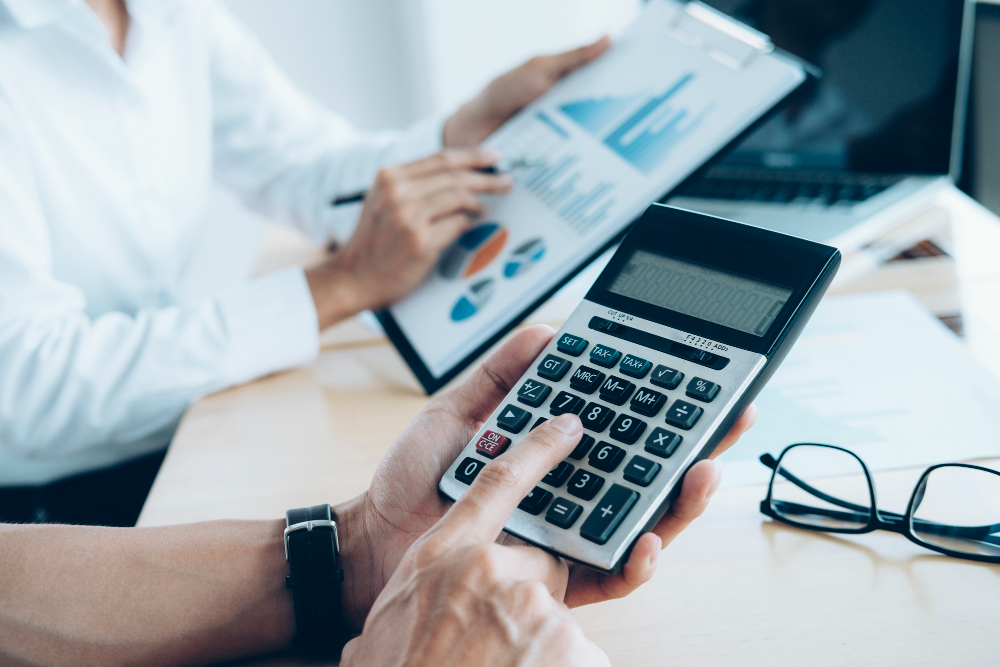 Investor or accountant analyzing financial statements with calculator and tablet showing charts.