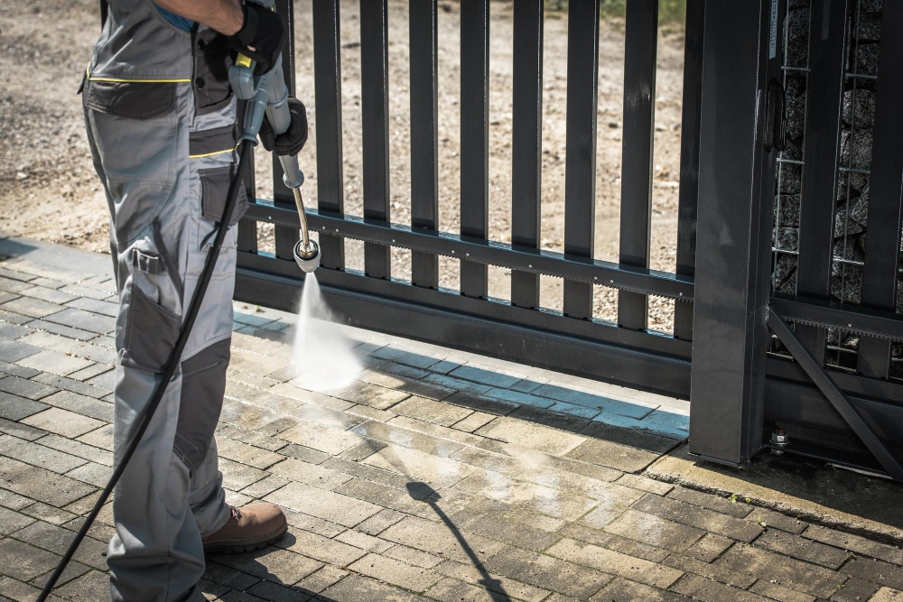 Contractor pressure washing a driveway with a high-pressure washer.