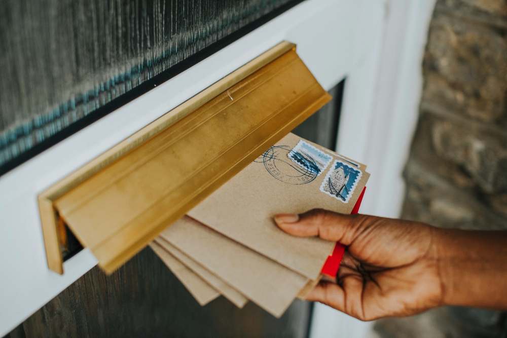 Hand placing a flyer/postcard through a letterbox, representing HVAC direct mail marketing.