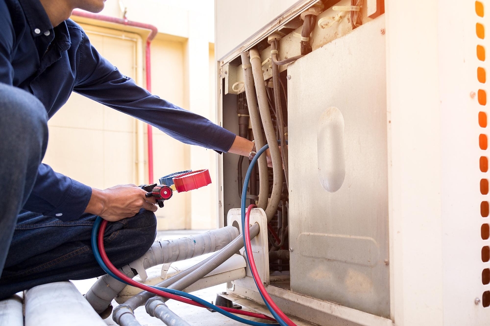 Close-up of technician using manifold gauges to run diagnostics on an HVAC outdoor unit.