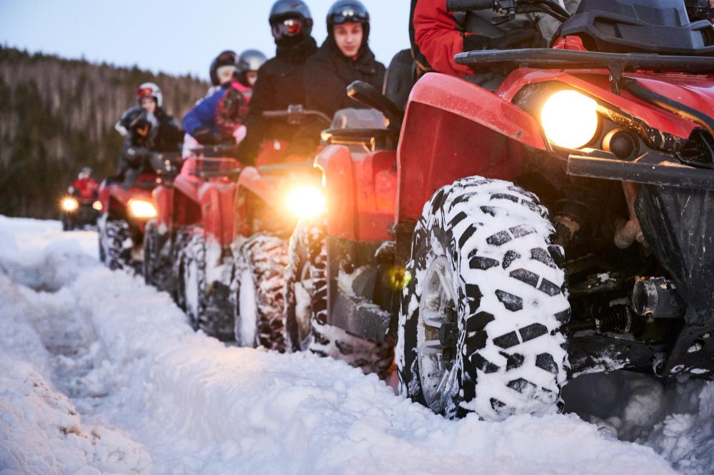line of red atvs on a snowed in road