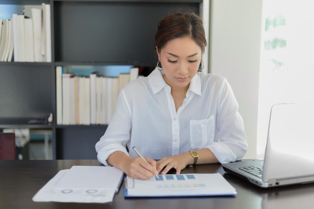 Woman reviewing accounting ledger at desk