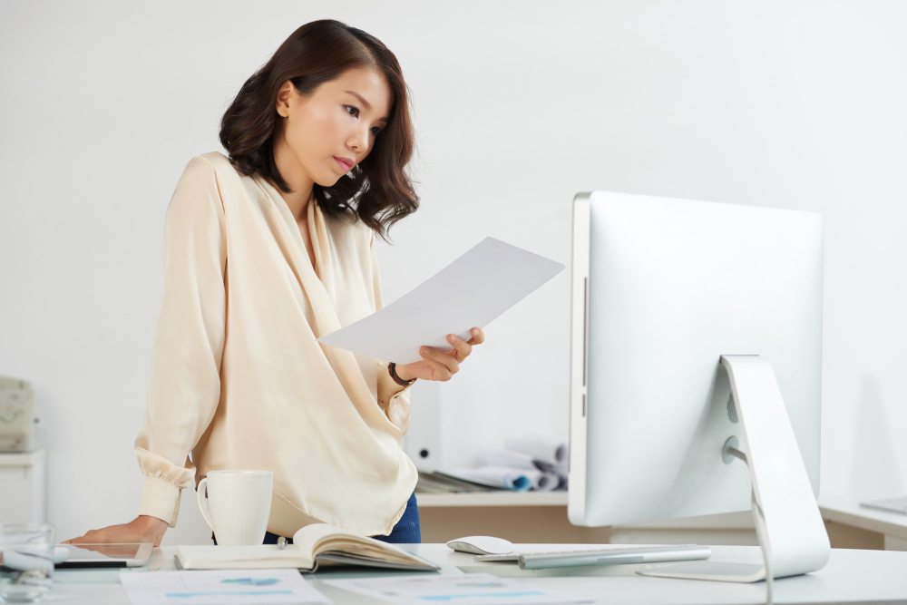 Businesswoman reviewing invoice and financial paperwork at desk