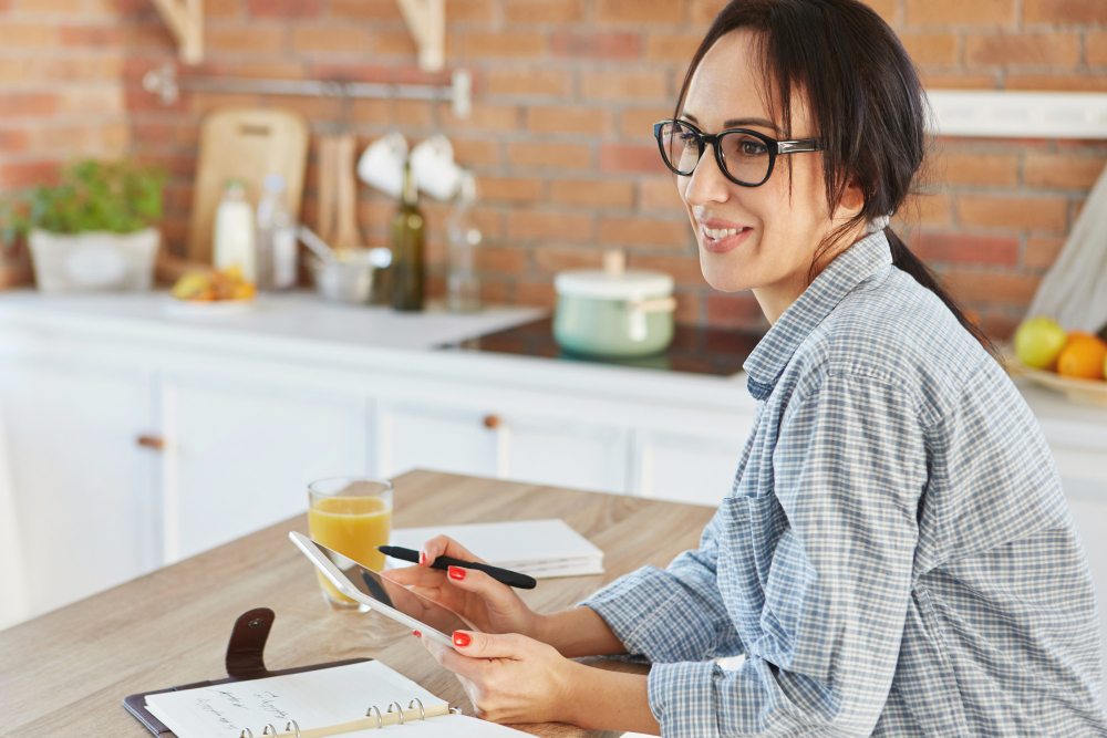 Woman using tablet in kitchen to manage cleaning service quote