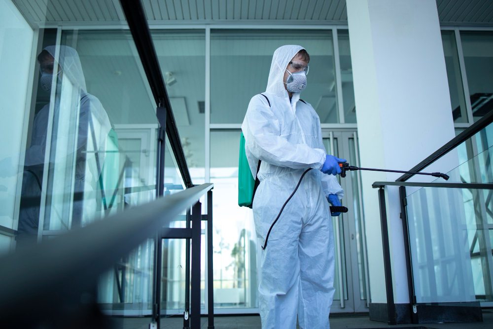 Cleaning technician in protective suit disinfecting indoor public area