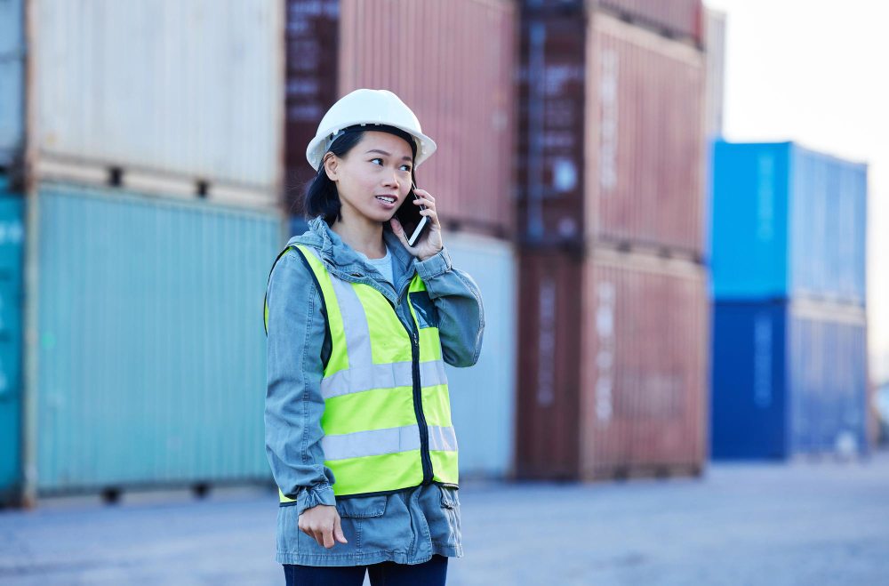 Logistics professional discussing shipment details on phone at port