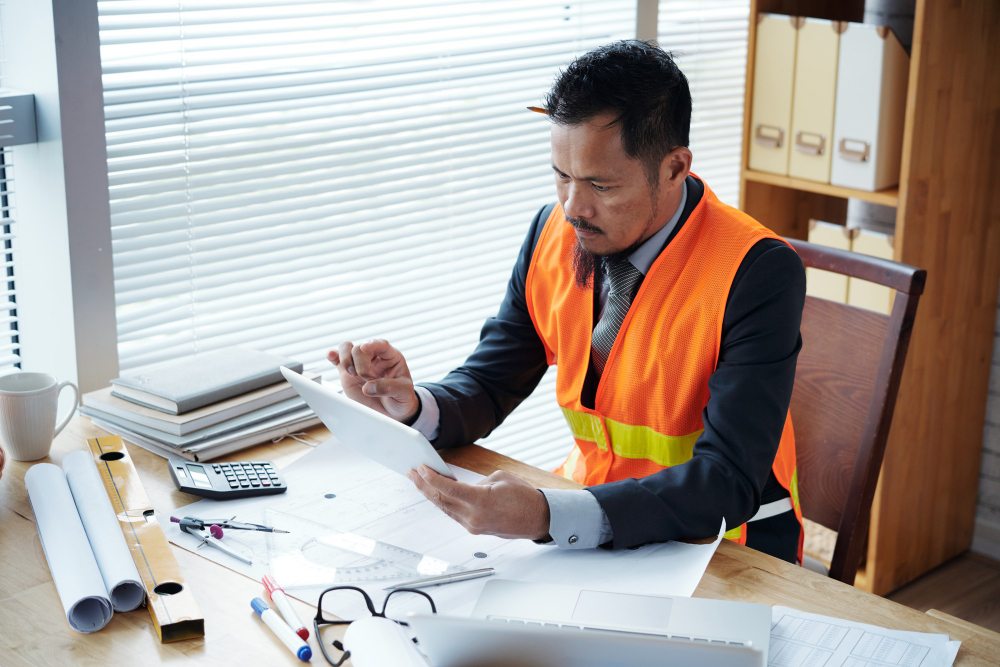 Civil engineer reviewing construction documents on tablet