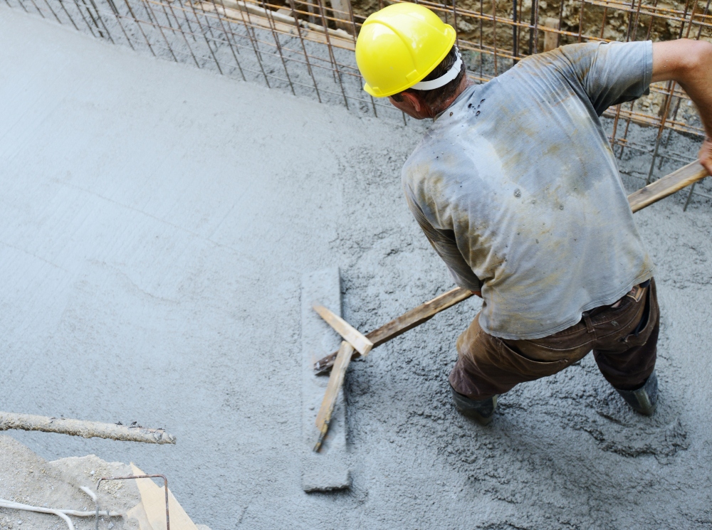 concrete contractor on work site spreading concrete