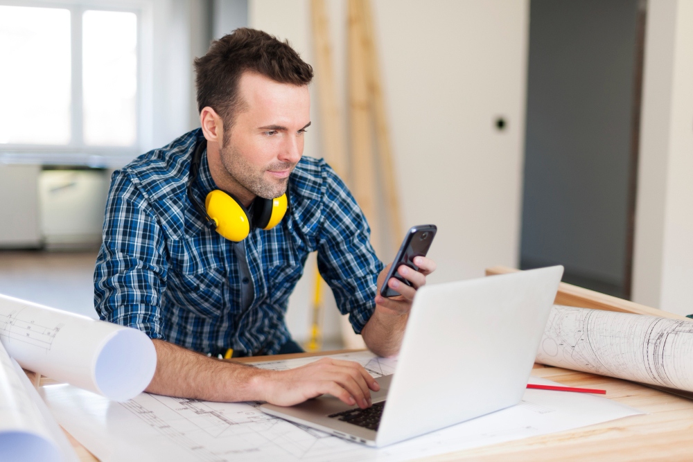 Construction worker preparing or sending quote on tablet