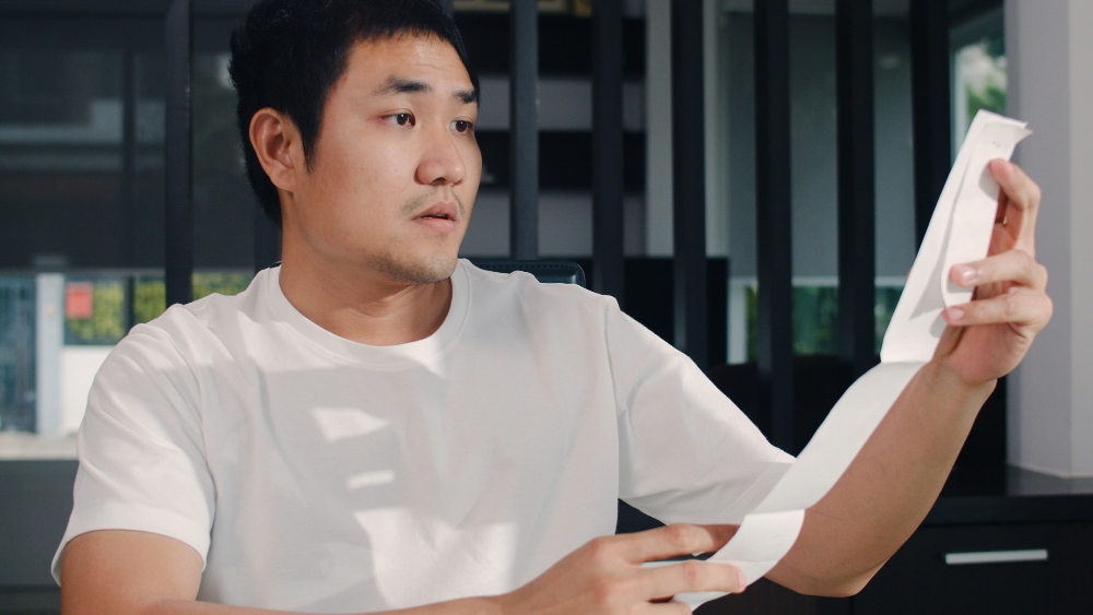 Persona que revisa recibos y documentos financieros en casa