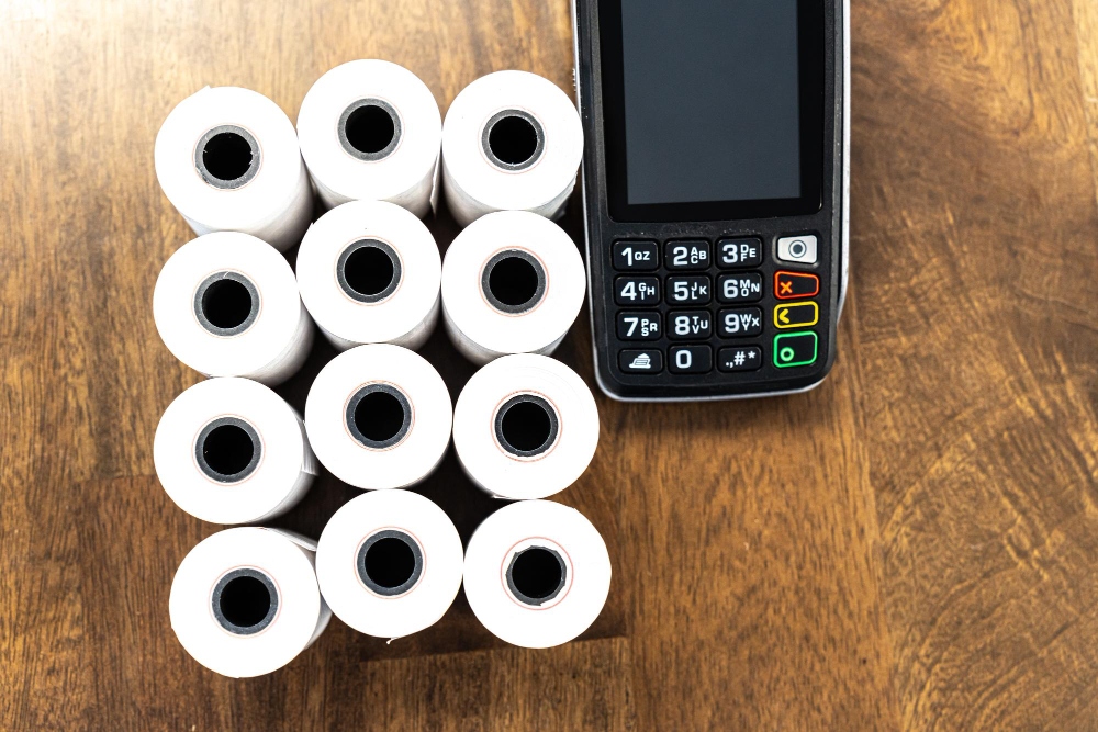Rollos de papel térmico para recibos junto a la máquina TPV