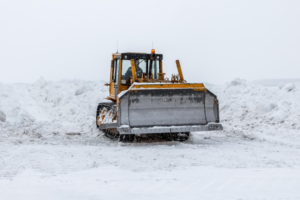 Excavadora desplazando nieve pesada durante una fuerte tormenta invernal