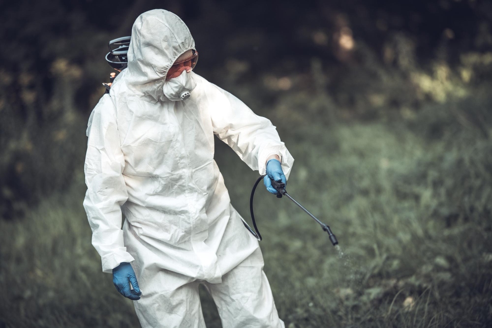 Trabajador rociando pesticidas en árboles para el control de plagas en el exterior