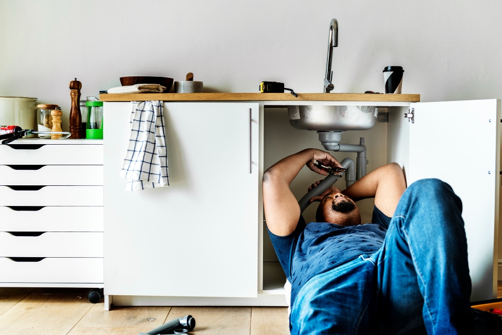 Professional plumber checking leaking pipes under sink

