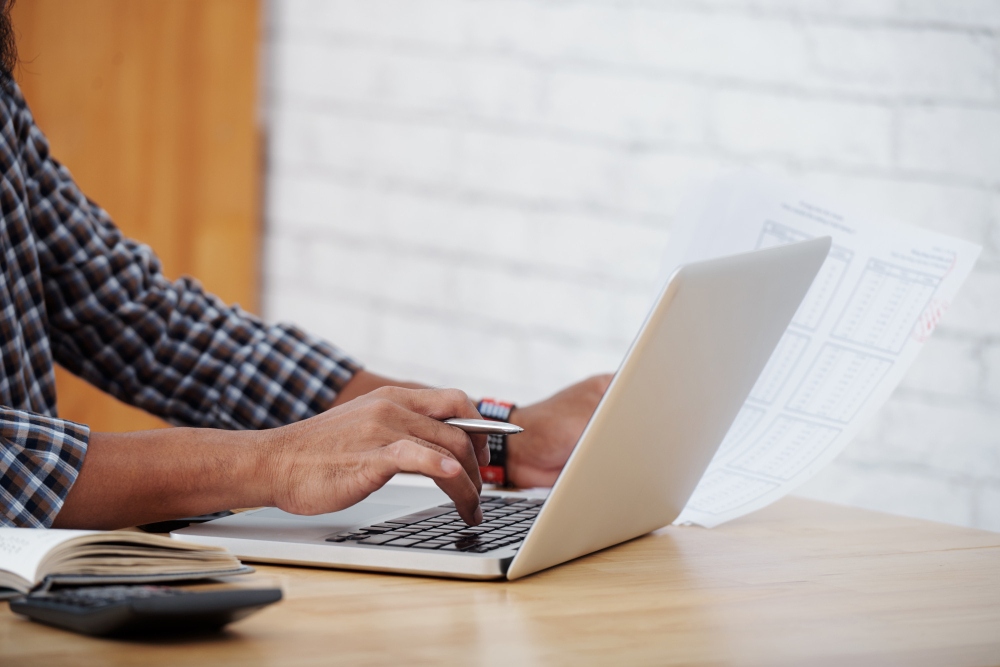 Persona que revisa los informes financieros y los extractos bancarios en un ordenador portátil