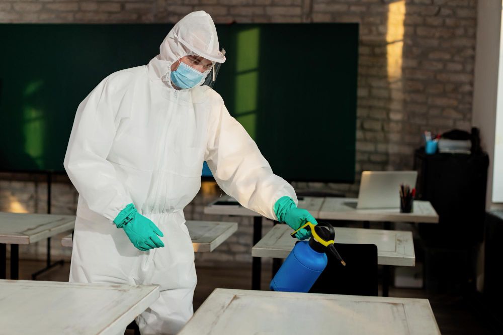 Technician in hazmat suit disinfecting commercial interior space