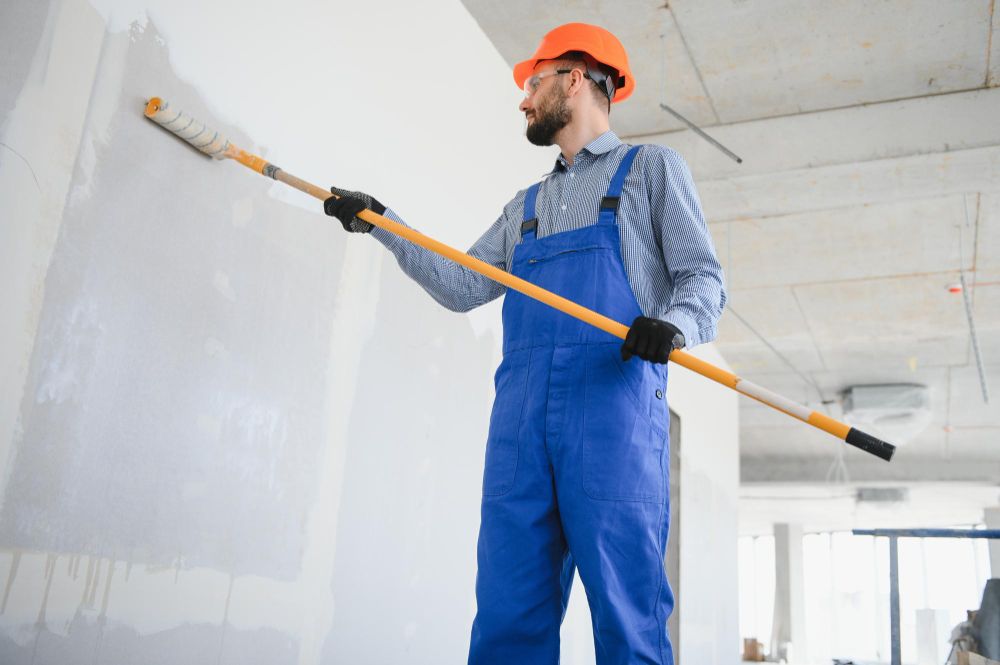 Painter in uniform applying paint to interior wall