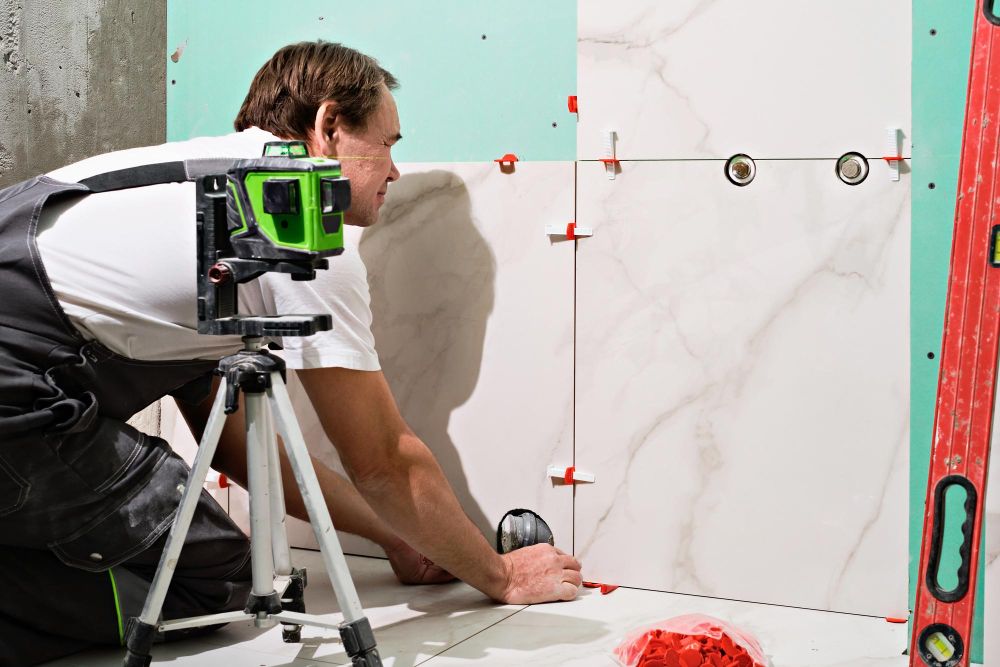 Professional handyman installing ceramic wall tiles in bathroom