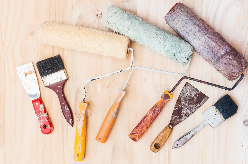 Painting brushes and tools arranged on wooden surface