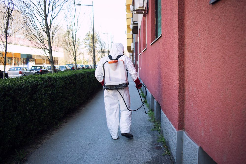 Pest control inspector in protective suit performing property treatment