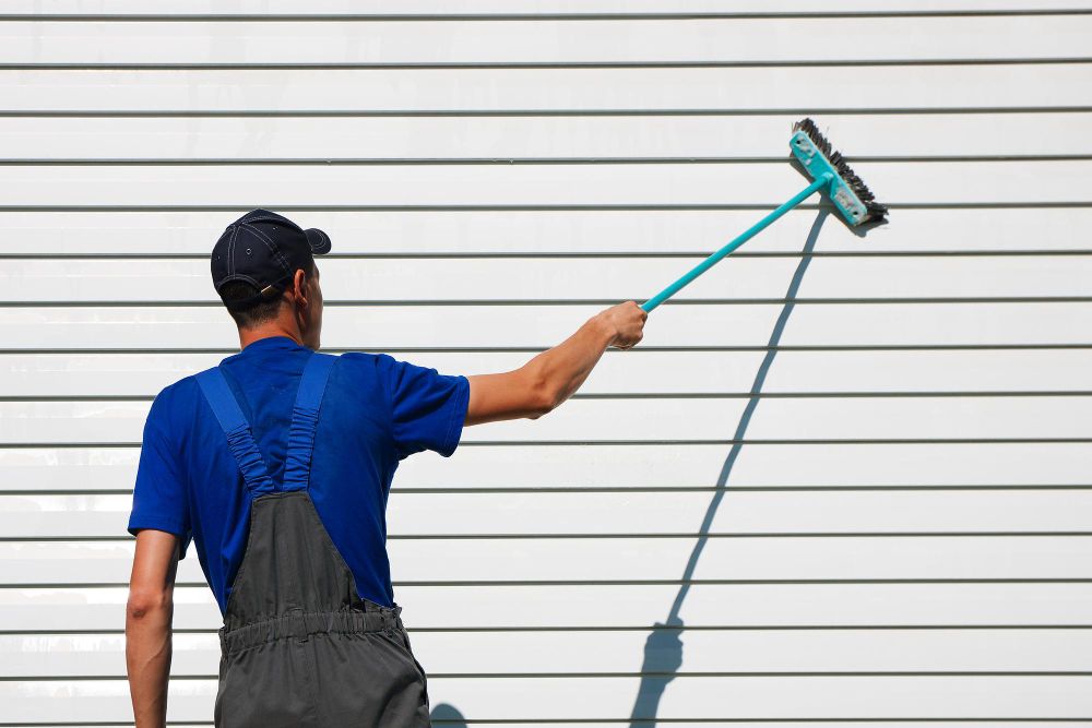 Worker cleaning an exterior wall with a brush