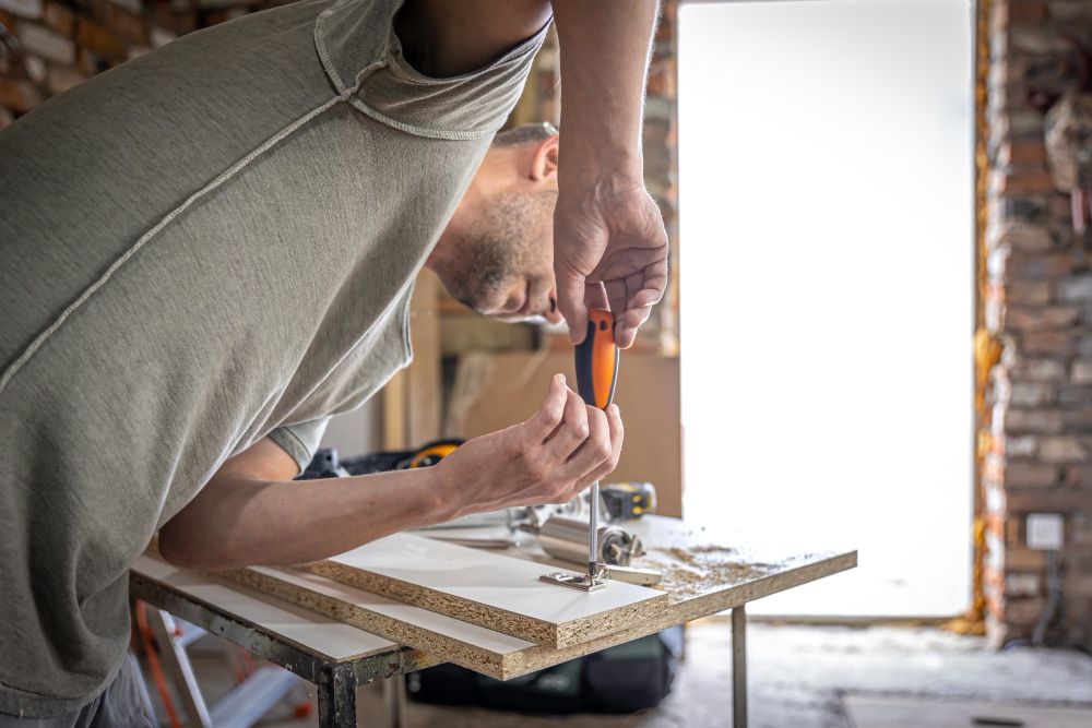Handyman fastening a wood fixture with a screwdriver
