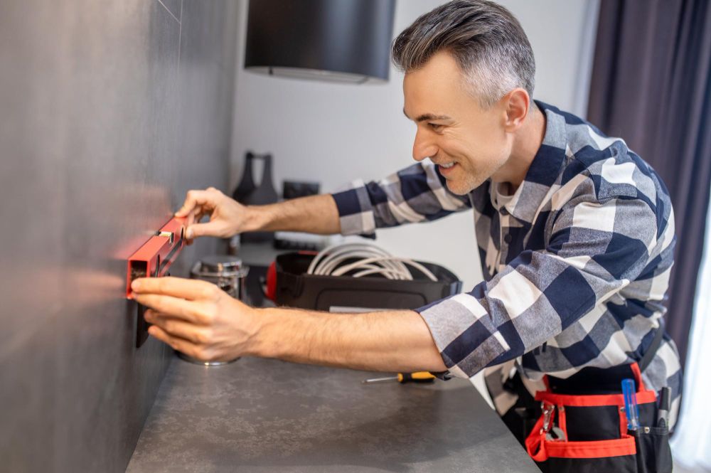 Handyman measuring near an electrical outlet during a repair