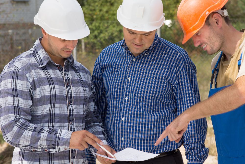 Construction and landscaping professionals discussing project documents on site