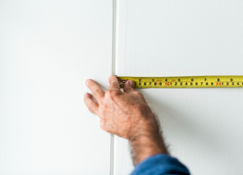estimator measuring interior walls and ceilings for an interior painting contract quote