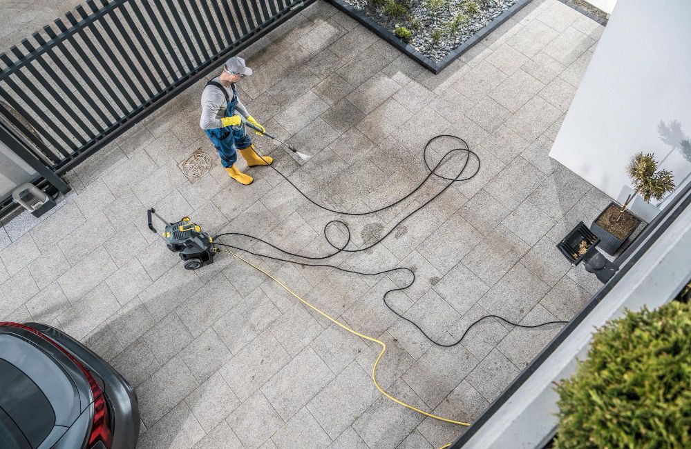 Homeowner pressure washing a concrete driveway