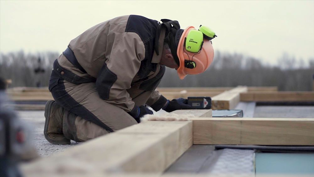 Roofing worker using a laser level during roof installation