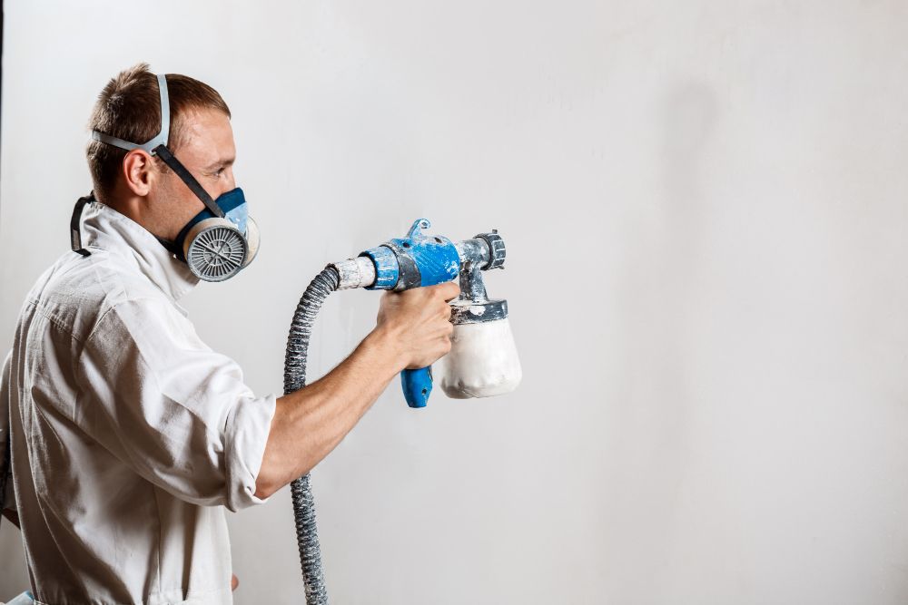 Commercial painter using a spray gun to paint a wall