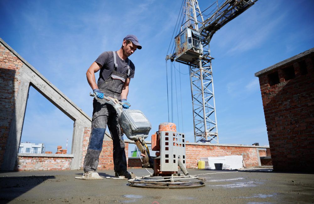 Worker leveling freshly poured concrete with specialist equipment