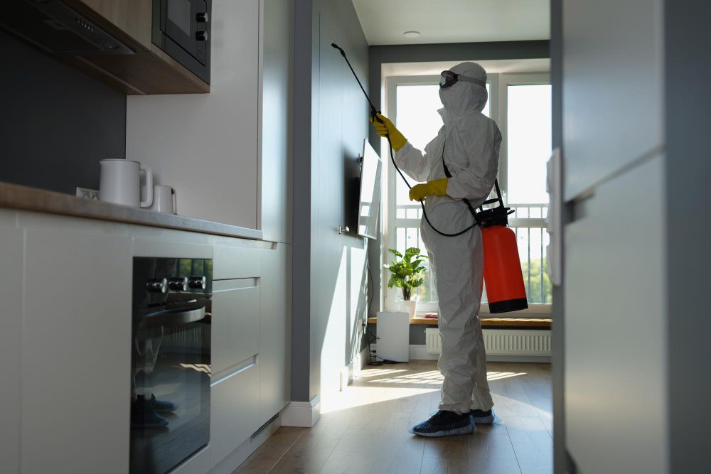 Pest control technician applying treatment around a property