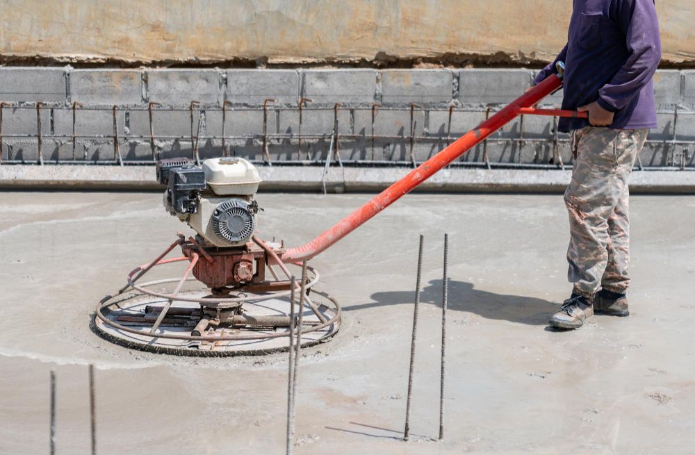 Worker finishing concrete with a power trowel