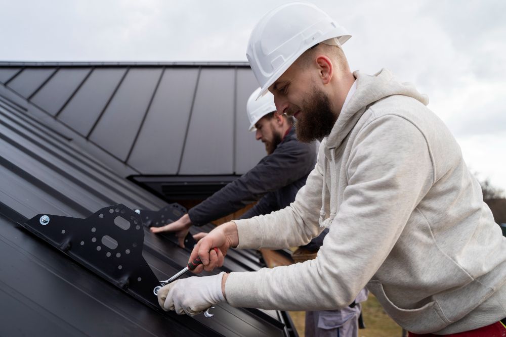 roofing technician installing metal roof panels on house