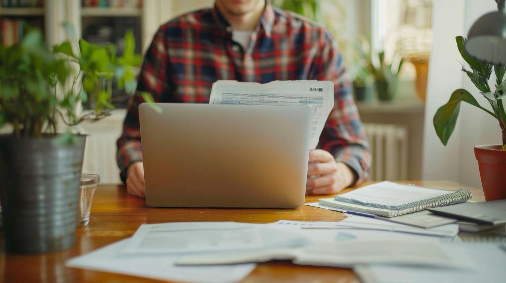 Freelancer preparing an invoice with a laptop and documents