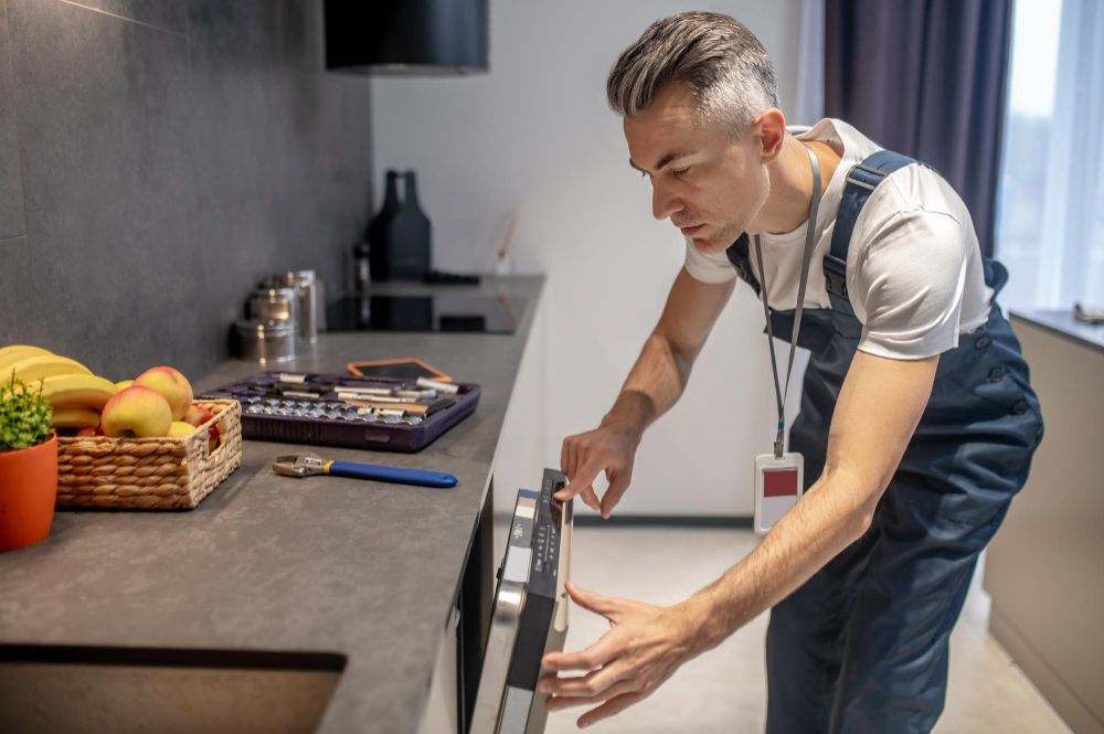 Appliance repair technician inspecting a dishwasher control panel