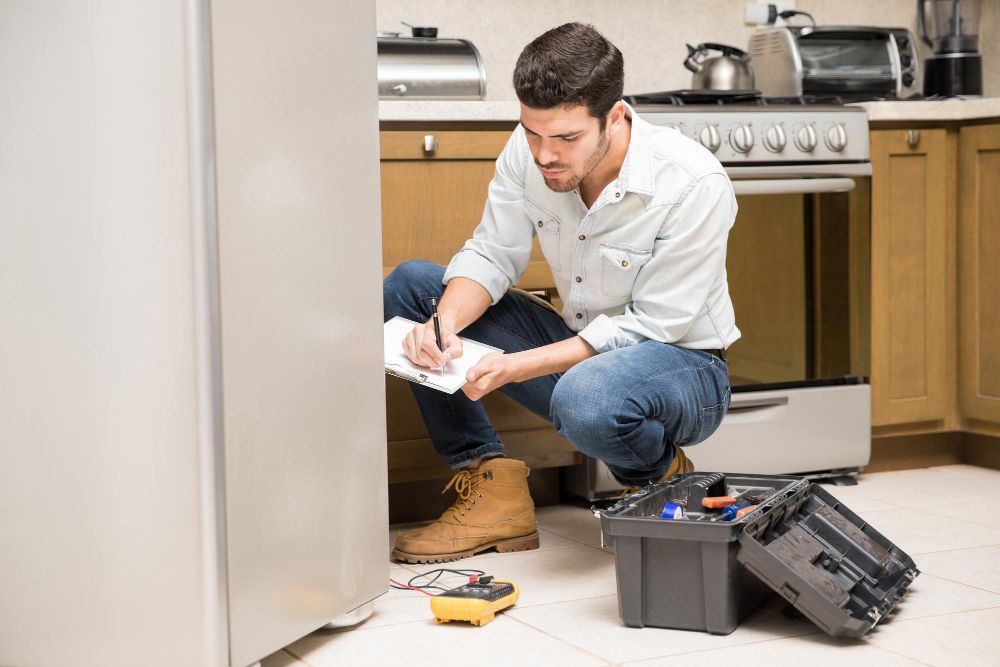 Appliance repair technician servicing a refrigerator in a home