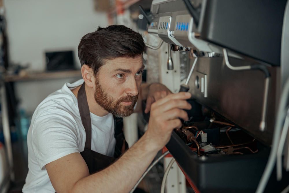 Technician repairing a coffee machine with a screwdriver
